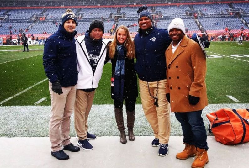 Photo of Sarah Bailey standing on football field with LA Rams coaches